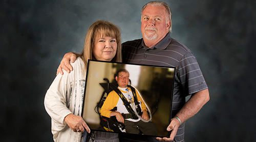 Parents holding a photo of their late, wheelchair- and ventilator- bound son.