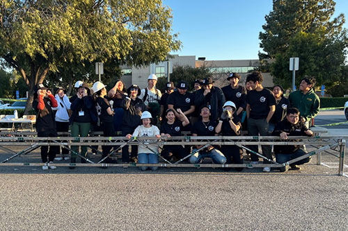 A group of over a dozen Cal Poly Pomona students celebrating their win in a Steel Bridge competition.