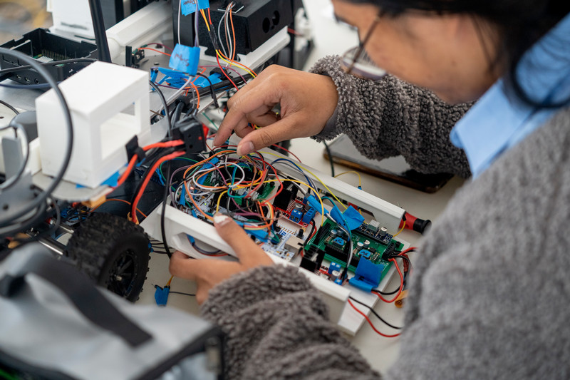 Cal Poly Pomona student working on wiring for an unmanned ground vehicle for the Northrop Grumman Collaboration Project