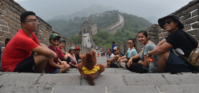 Students on the Great Wall of China with a brown stuffed animal