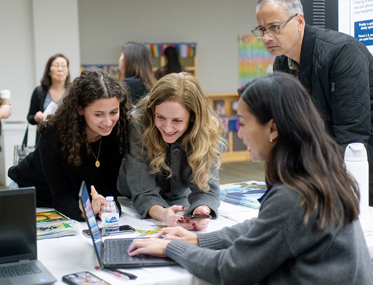 A student and supporter are helped out by admissions staff at a table.