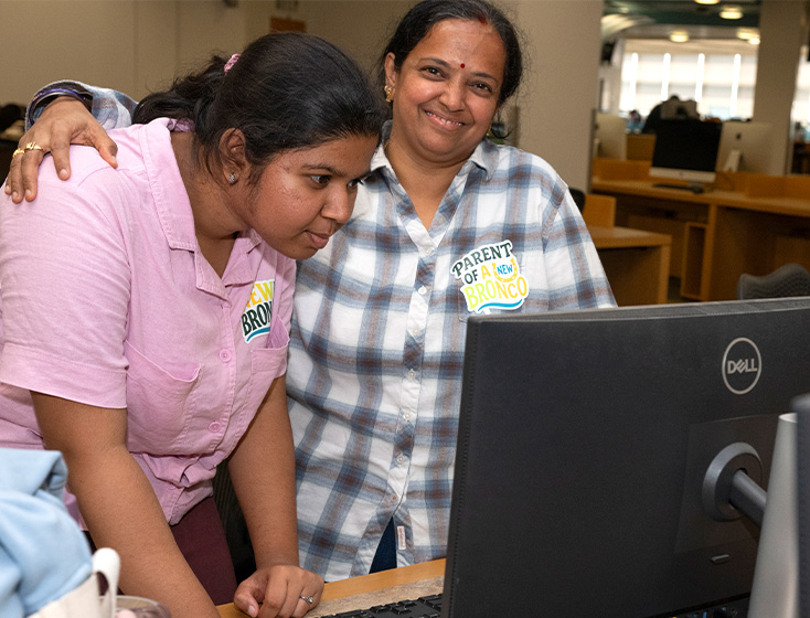 A student and her supporter fill out an application at a desktop.