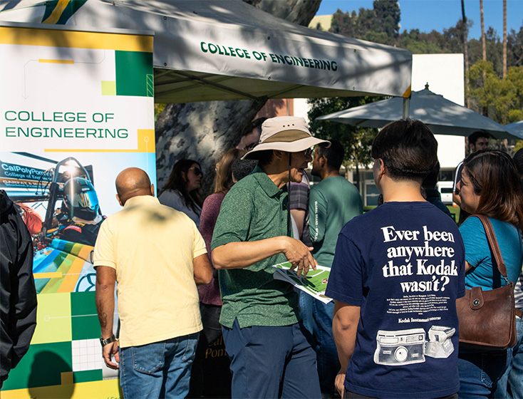 A faculty member speaks about the College of Engineering with a student in front of their booth.