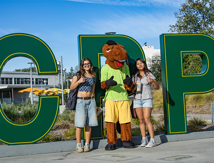 Two girls posing with a horse mascot in front of lifesize letters spelling "CPP"