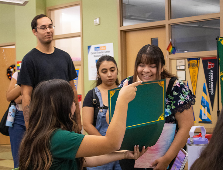 A student grins at the on-the-spot admission certificate being shown to her by an outreach counselor.