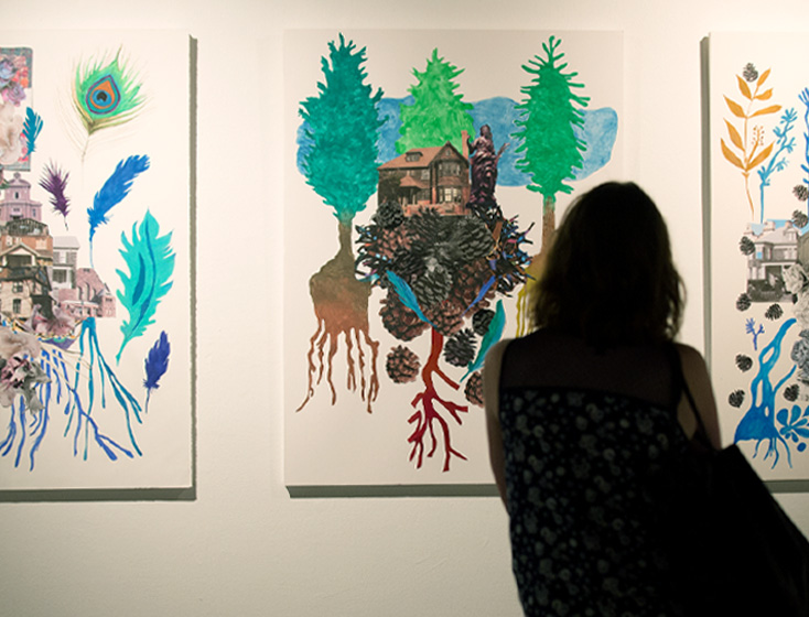 A student looks at artwork hung up at the Kellogg Art Gallery.