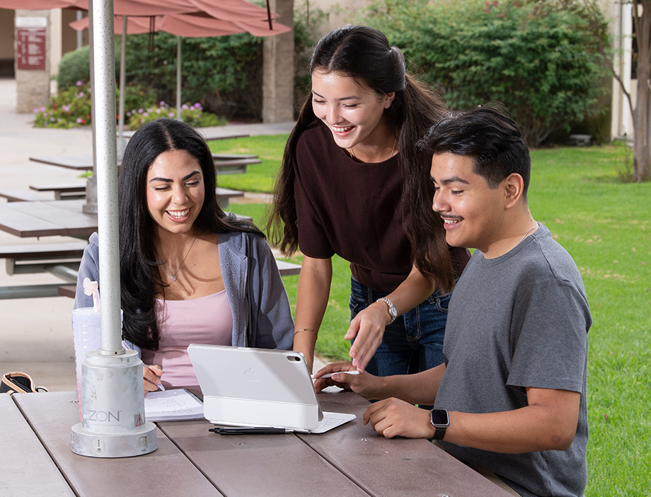 3 students together looking at a laptop