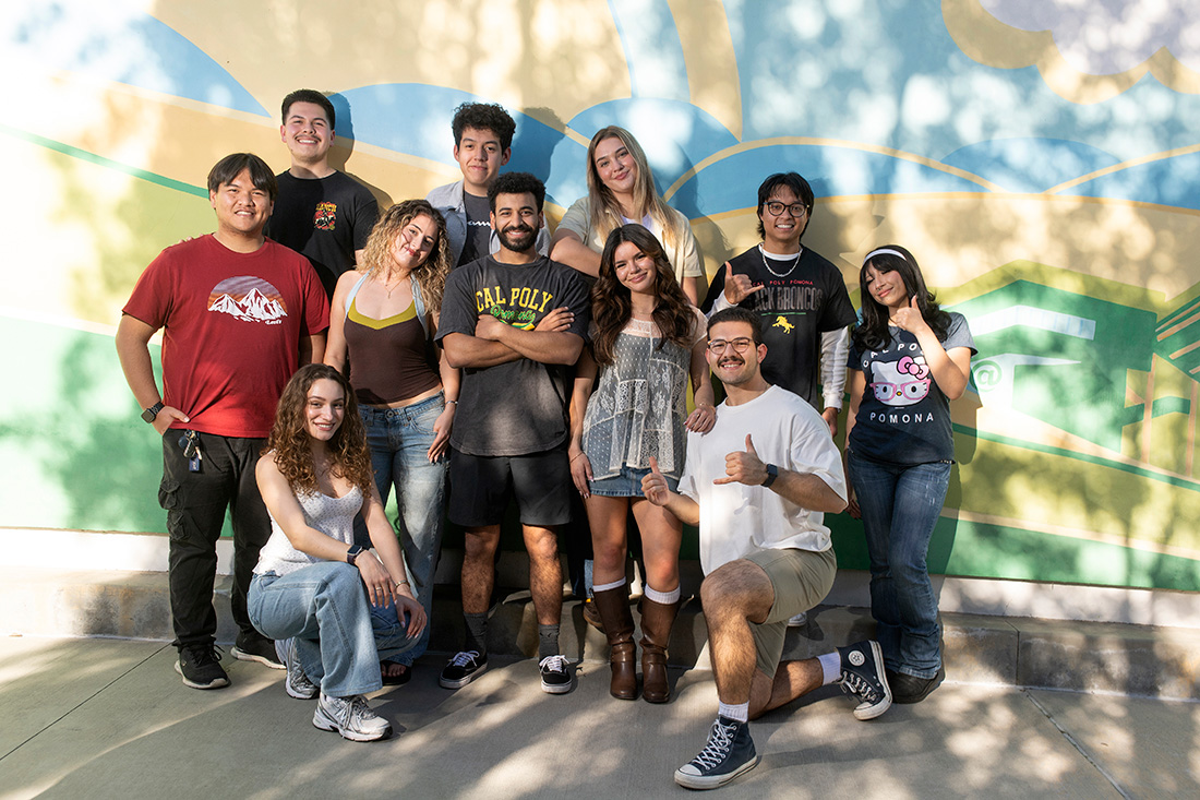 A group of smiling students pose in front of the mural at Parking Structure II