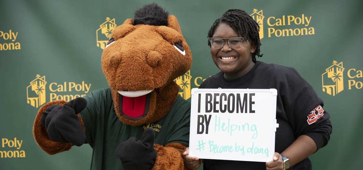 A CPP student posing with Billy Bronco