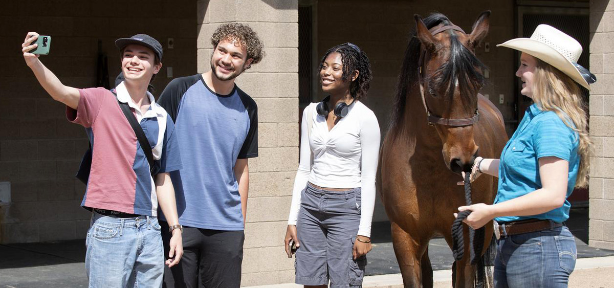 Cal Poly Pomona students taking photos with one of the horses on campus