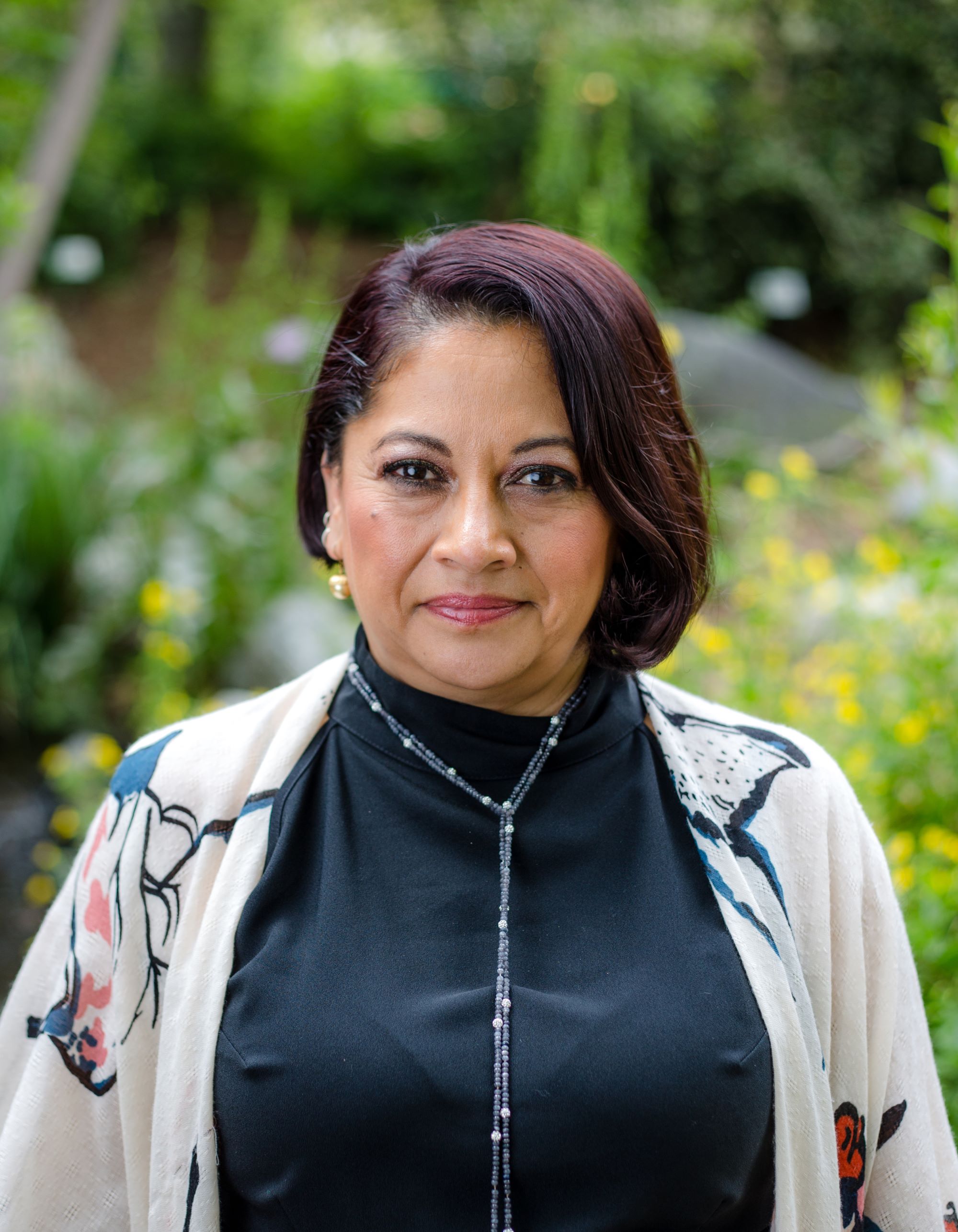 A woman smiling in front of some greenery