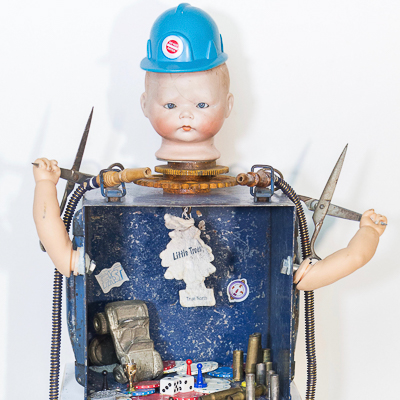 Gina M.  Runs With Scissors from the Toy Box Kids Series, 2018  assemblage, blue box, doll head, scissors, bullets, air freshener, bronze baby shoes  31 x 14 x 12”  Courtesy of the artist