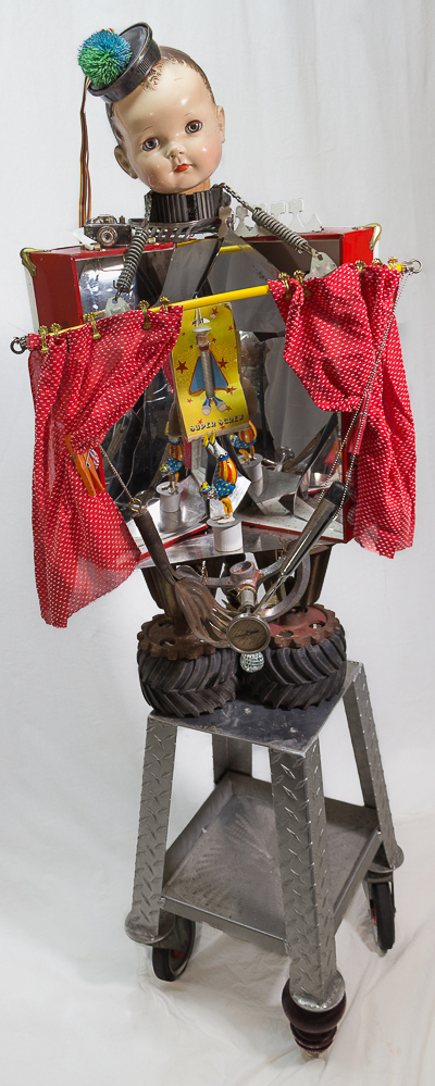 Gina M.  The Big Show from the Toy Box Kids Series, 2018  assemblage, convex mirror shards, toys, step stool, toy tires, curtain and hardware  68 x 24 x 24”  Courtesy of the artist