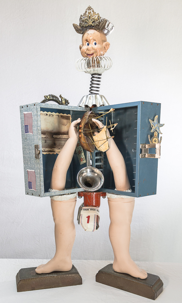 Gina M.  Not A Drill from the Toy Box Kids Series, 2018  assemblage, blue box, doll parts, spring, gold table, horn, cabinet hardware  30 x 18 x 12”  Courtesy of the artist