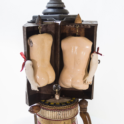 Gina M.  Ass Clown from the Toy Box Kids Series, 2018  assemblage, doll bodies, rusty box, scrabble letters, shoe horns  36 x 14 x 17”  Courtesy of the artist