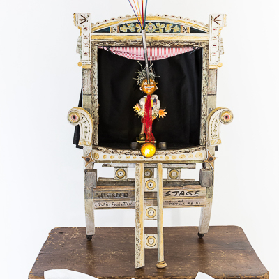 Gina M.  Whirled Stage from the Toy Box Kids Series, 2018  assemblage, child desk, puppet, paper, spotlights, found objects  62 x 36 x 20"  Courtesy of the artist