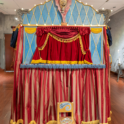 Gina M.  The Show Must Go On, 2019   silk fabric and fringe, battery lights, repurposed folding screen, oil paint on board, found puppets and toys  90 x 120 x 36”  Courtesy of the artist