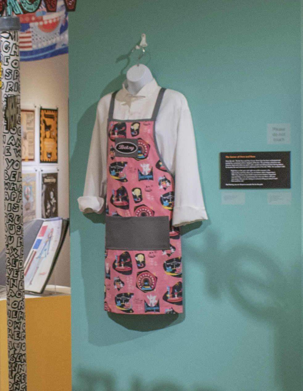 Pink and Grey Apron decorated in Fauxtopia design graphics like Hot Air balloon, Blank mascot, and amusement rides