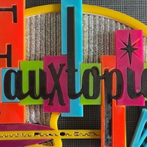 a small 3d model of a fauxtopia entrance sign with a blue arrow pointing towards the direction of the entrance. The letters of Fauxtopia are backed by rectangular shapes of various colors.