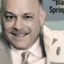 The cover of a TV guide with G.E. McAtnoff holding onto Fauxtopia's mascot, Blank. The text at the top reads "The fine blurry line between TVLand and the real world pg. 19." The tagline text reads "He wants to make sure your screen is 'Blank' this spring season pg. 70."