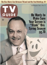 The cover of a TV guide with G.E. McAtnoff holding onto Fauxtopia's mascot, Blank. The text at the top reads "The fine blurry line between TVLand and the real world pg. 19." The tagline text reads "He wants to make sure your screen is 'Blank' this spring season pg. 70."