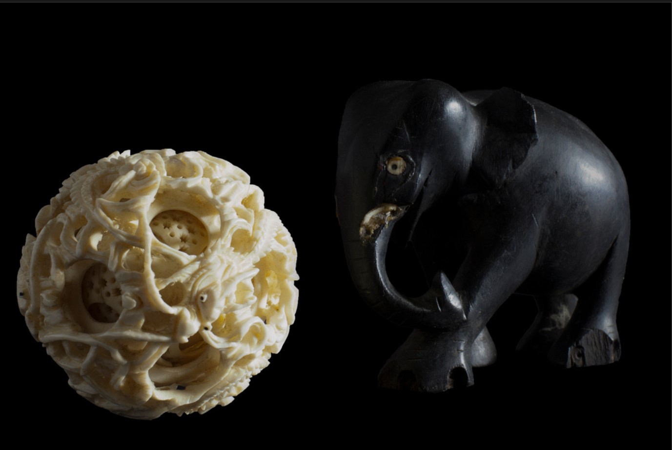 textured white ball next to black wooden elephant