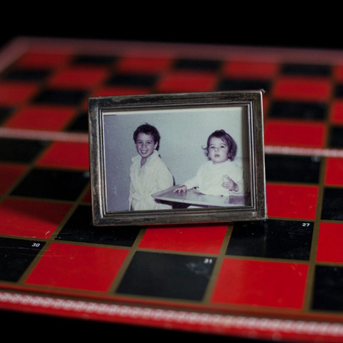 framed photo of siblings on top of a chess board 