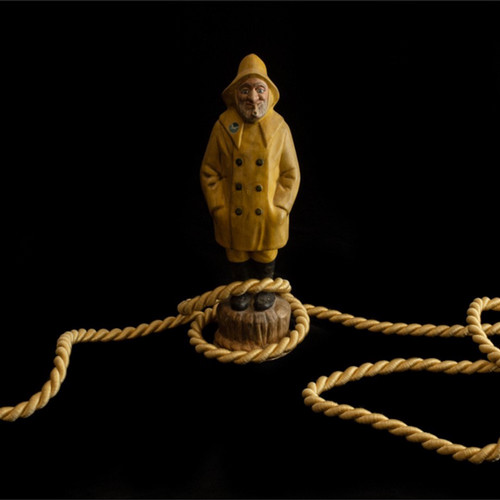 small statue of a man in a yellow coat with rope around the floor
