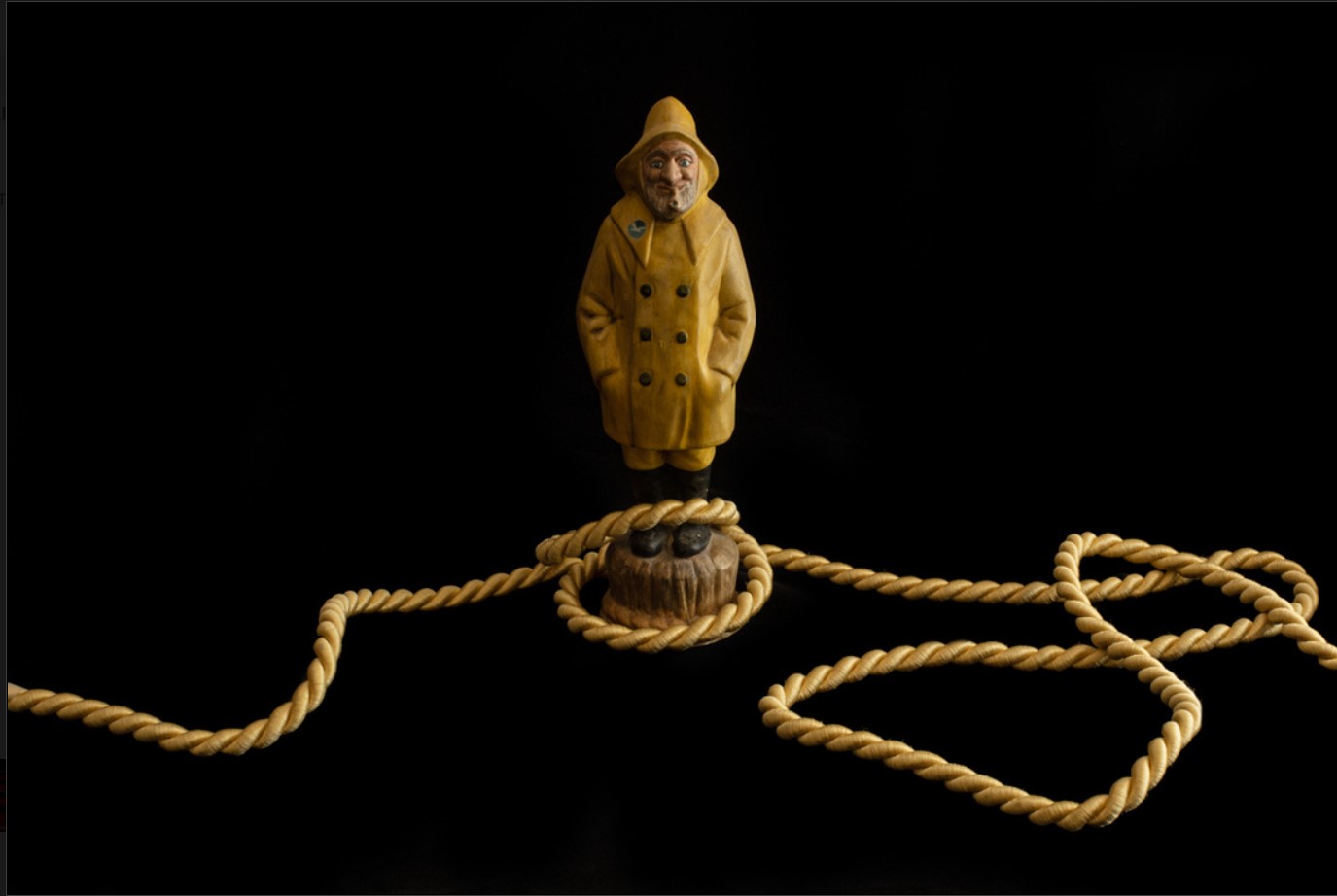 small statue of a man in a yellow coat with rope around the floor