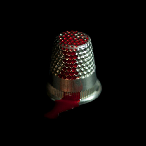 sewing thimble with red liquid on top