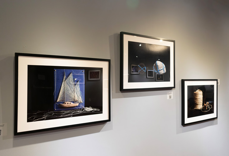 installation view picture frame with a picture of a blue twine boat and next to it a picture frame with twine around a dog