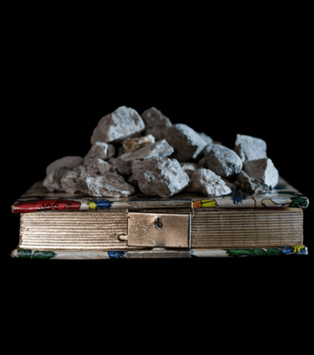 black background with a book and pile of rocks on it.