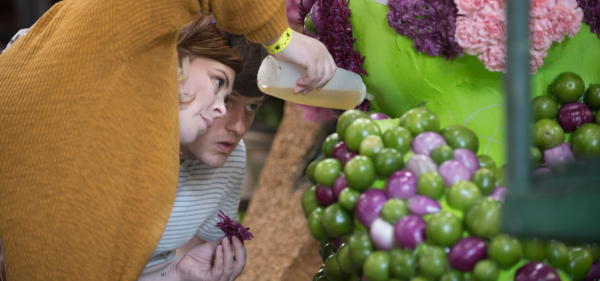 Two volunteers glue flowers on the 2019 Cal Poly Universities Rose Float. 
