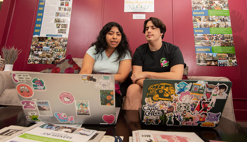 A female and male student work on a research project together with their laptops.