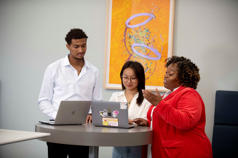 Students working with Professor in front of their laptops
