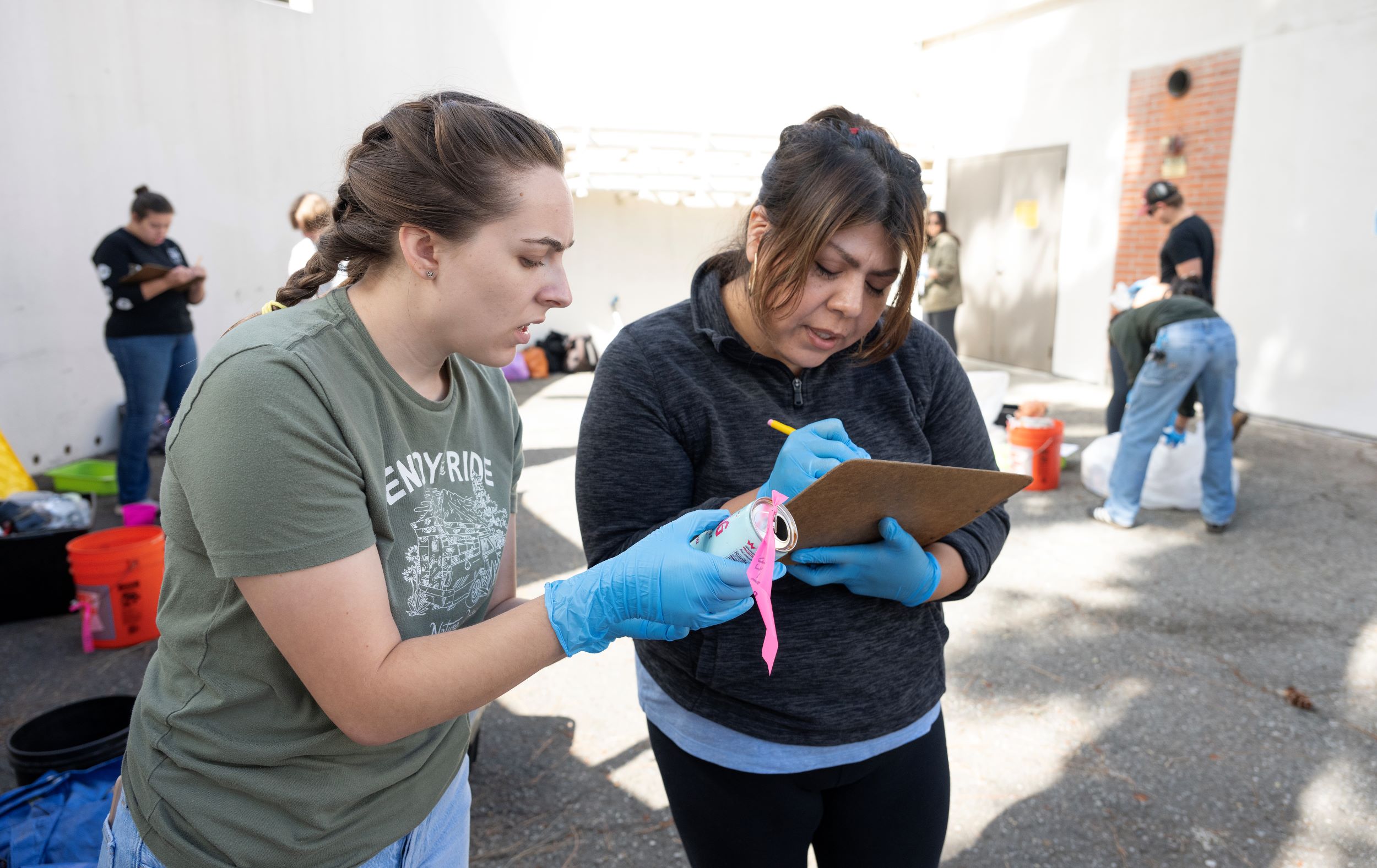 Two female anthropolgy students take inventory of trash found during a class excursion.