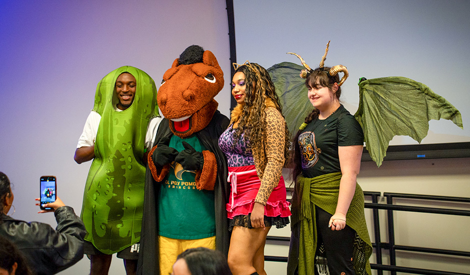 Students dressed as a pickle, leopard and dragon pose with Billy Bronco during Fright Fest