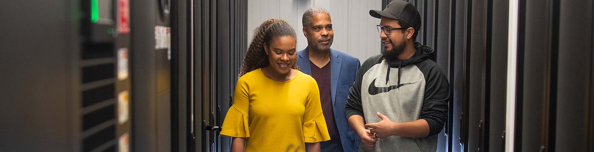 three people walking and talking in a server room