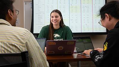 students collaborate at a desk in a Collins College of Hospitality classroom