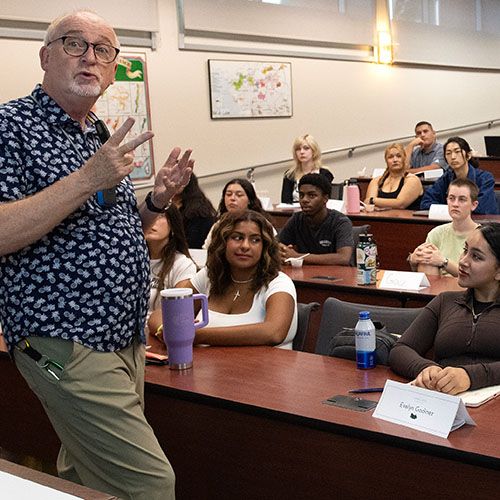a picture of a faculty member giving a lecture in a basic room