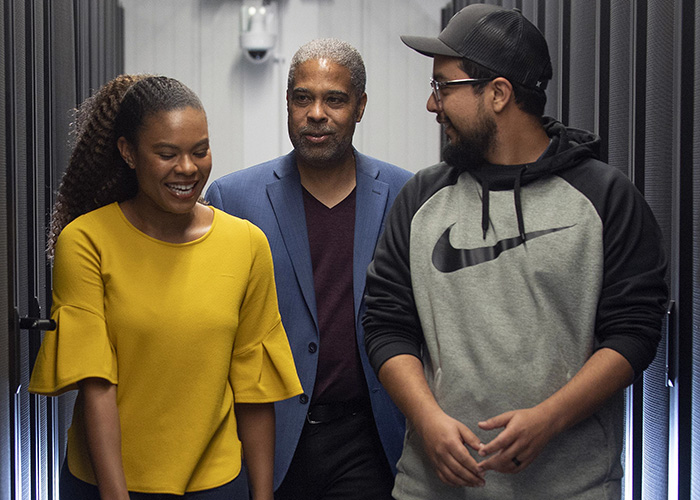 three people walking in a server room