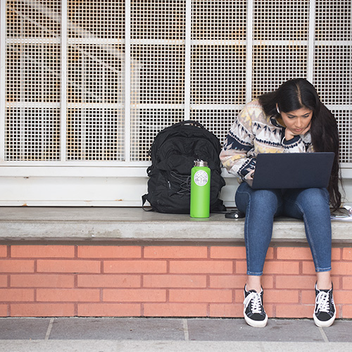 student sitting outside of a stairwell