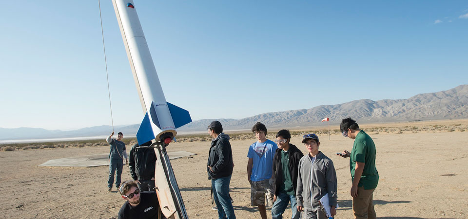 group of students preparing to launch a rocket in the desert