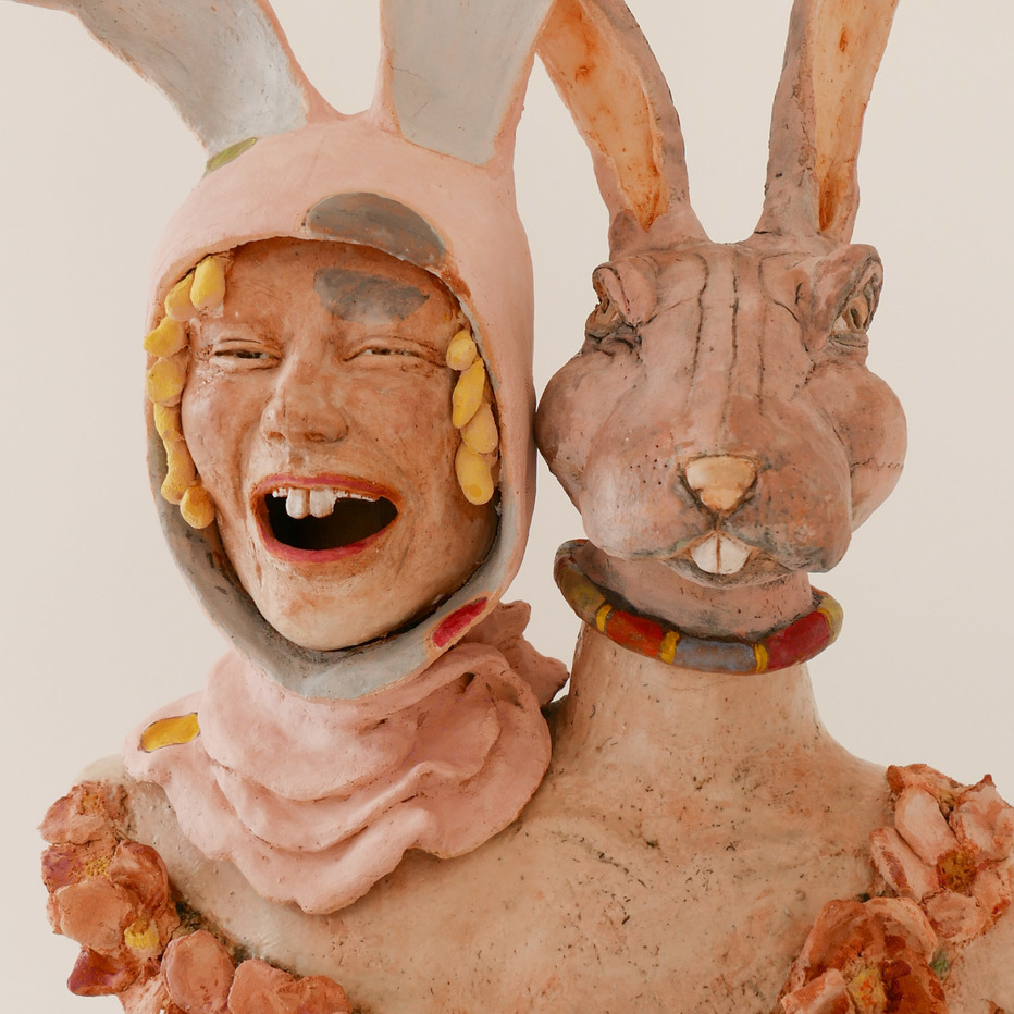 Lisa Crane, Folie a Deux, 2018. Clay. 22 x 17 x 9“ Courtesy of the artist. A sculpture of a woman in a bunny hat next to a rabbit head sculpture