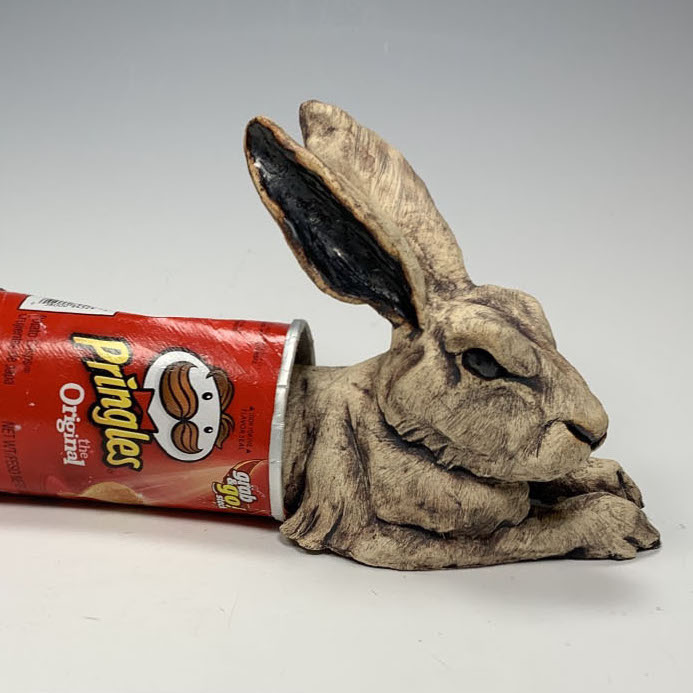 Deana Bada-Maloney, Splitting Hare, 2019. Stoneware and found object. 5 x 12 x 5" Courtesy of the artist.  Deana Bada-Maloney, Nectar, 2019. Stoneware and found objects. 7.5 x 4 x 2.5" Courtesy of the artist A sculpture of a hare caught in between a canister of ships.