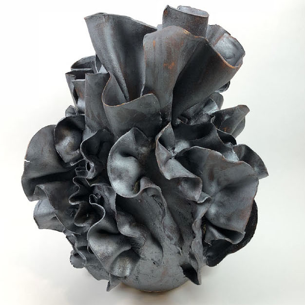 Caroline Blackburn, No 440, 2019. Clay, high fire, stoneware. 20 x 18 18" Courtesy of the artist. A black round object with ribbon like extrusions 