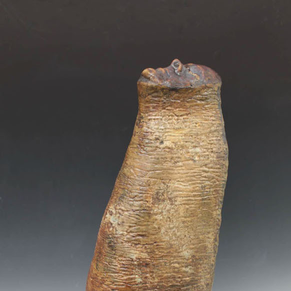 Matt Brugger, Portrait, 2019. Glazed ceramic 32 x 7 x 14.4" Courtesy of the artist. A brown/tan colored worm like shape with the face of a person facing upwards