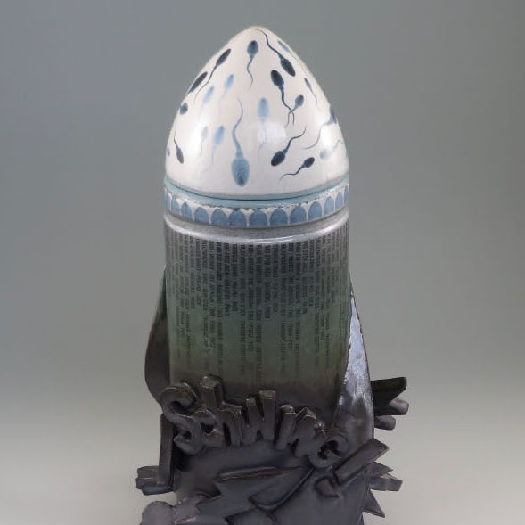 Kevin Eaton, Cookie Jar No. 2, 2018. Ceramic 16 x 9.5 x 9.5” Courtesy of the artist. A rocket shaped sculpture with text and a cloud on the bottom