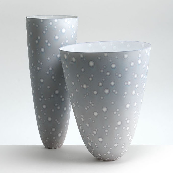 Mark Goudy, Relational Forms (#878, 935), 2019. Unglazed porcelain, soluble metals: gold, cobalt, chromium. 9 x 7” dia. and 11 x 4.5” Courtesy of the artist. Two scultptures of cup or vase like objects in grey color with white dots all over
