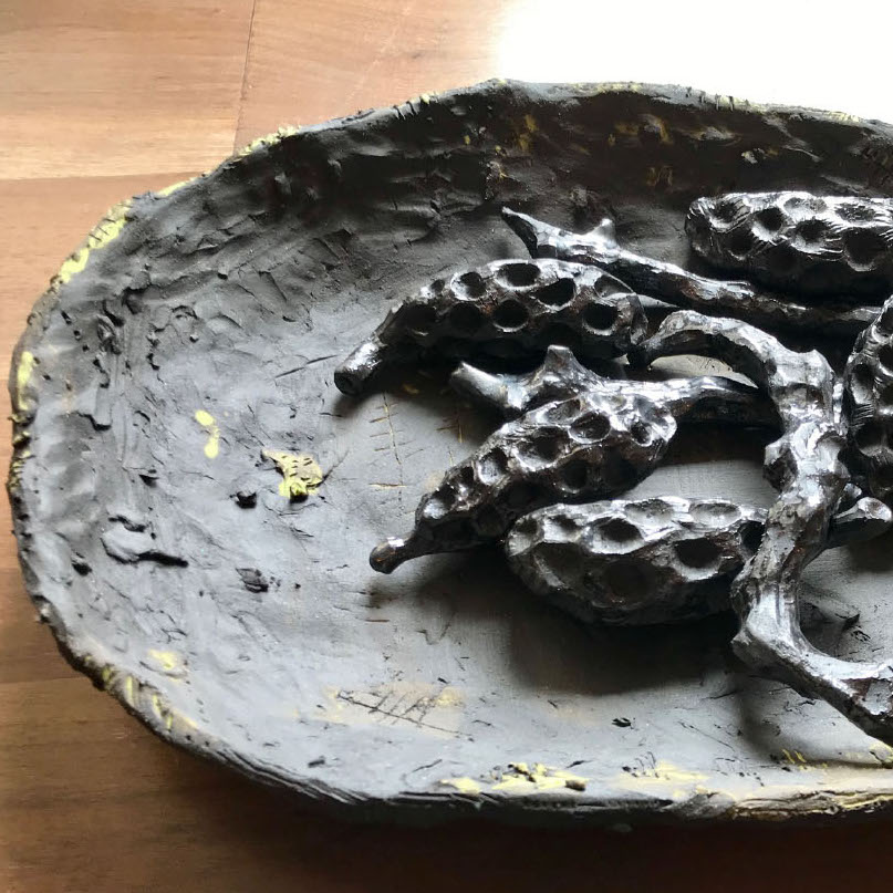 Sharon Hardy, Afterburn, 2019. Ceramic. 3 x 11 x 15” Courtesy of the artist. A sculpture of a plate with seed pods